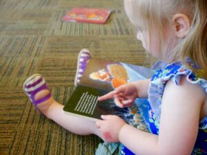 Petite fille feuilletant un livre et découvrant une histoire lors d’un atelier pour enfants